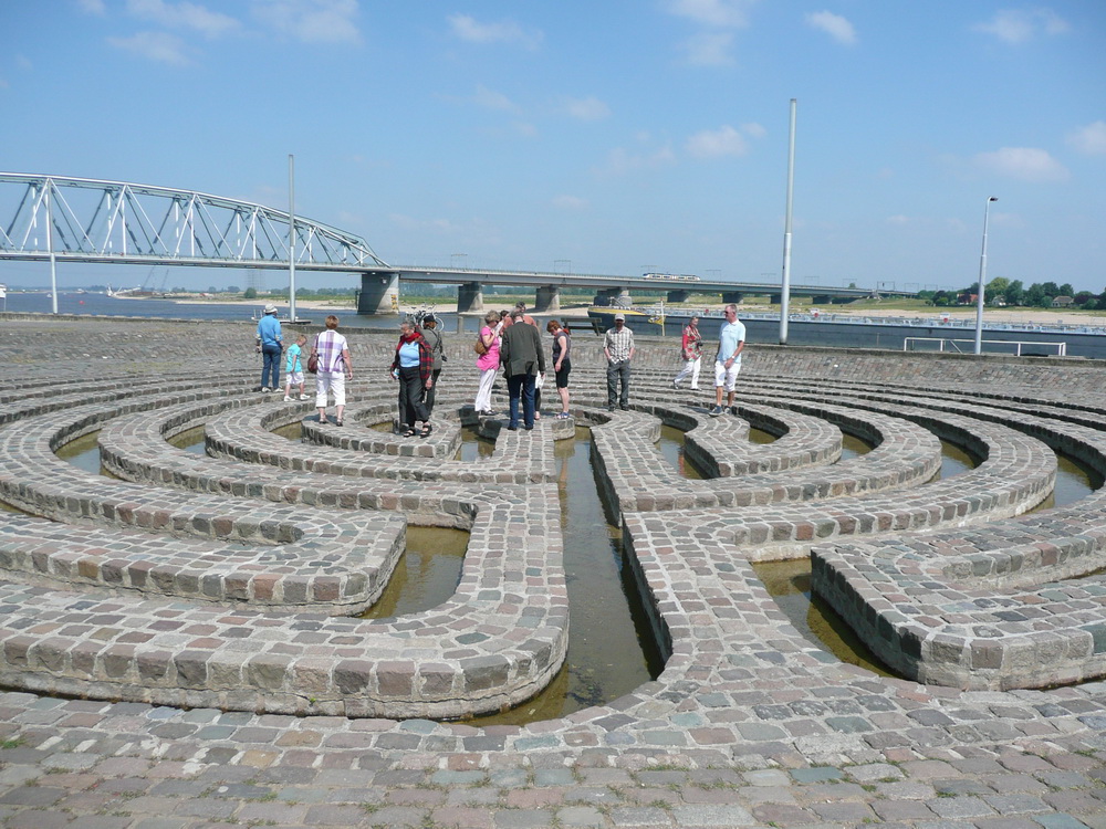 People standing on the labyrinth, river and bridge in the background, closer view