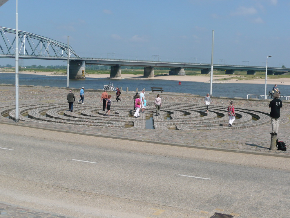 People standing on the labyrinth, river and bridge in the background